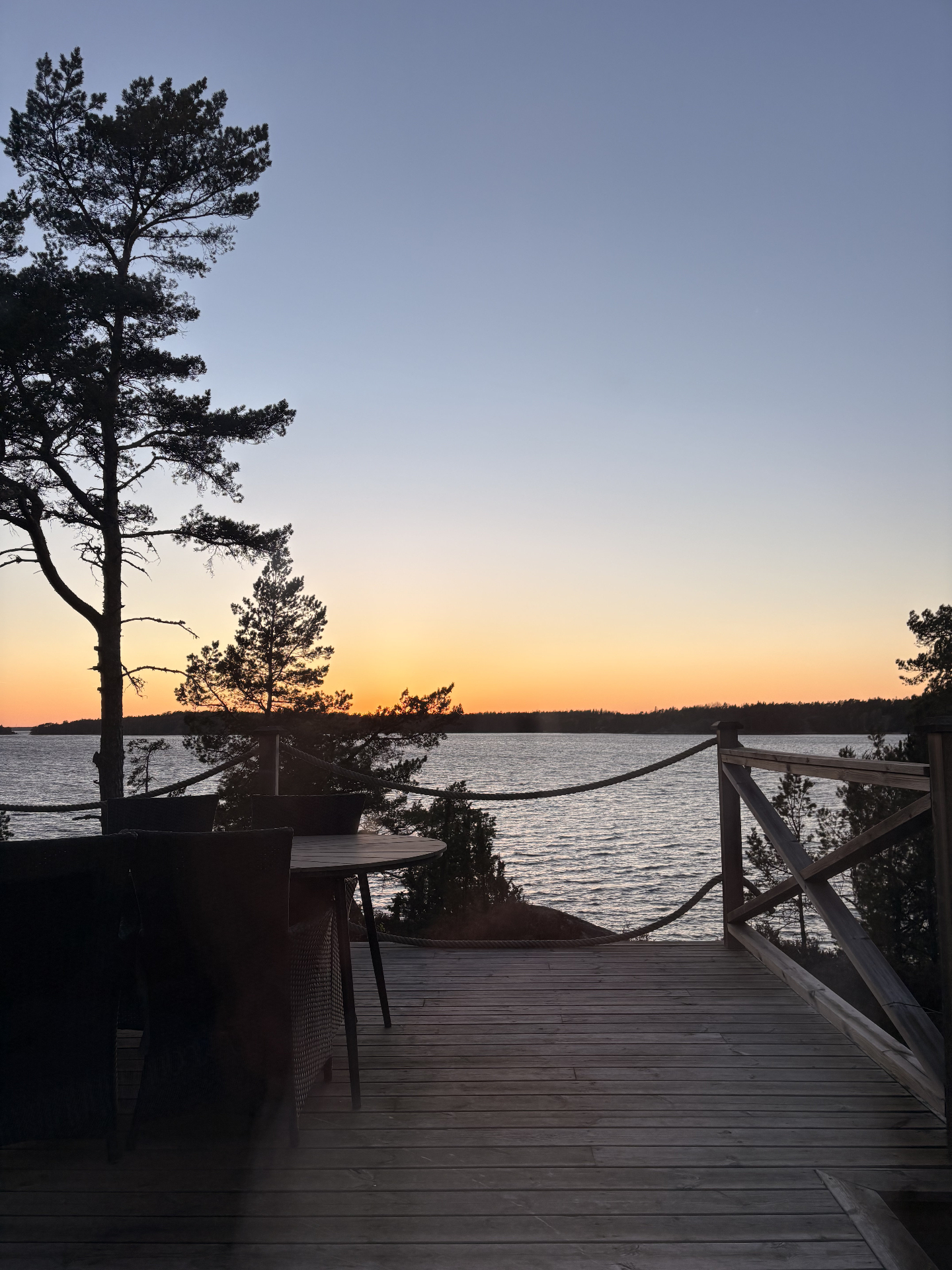 Altanen i skymning med bord och repräcke över stilla vatten